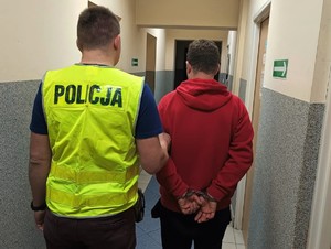 Zdjęcie przedstawia policjanta wraz z zatrzymanym mężczyzną.