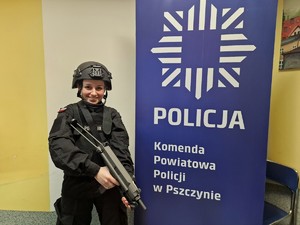 Zdjęcie przedstawia: uczennicę klasy mundurowej w kamizelce kuloodpornej, kasku z bronią.