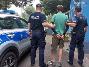 Zdjęcie przedstawia dwóch umundurowanych policjantów z zatrzymanym mężczyzną.