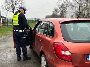 Zdjęcie przedstawia: policjanta ruchu drogowego podczas kontroli kierującego samochodem osobowym.