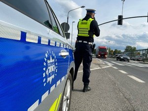 Zdjęcie przedstawia: policjanta ruchu drogowego podczas czynności pomiarowych.