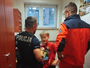 Zdjęcie przedstawia policjanta i ratownika medycznego ze znalezionym chłopcem.