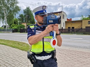 Zdjęcie przedstawia: policjanta podczas pomiaru prędkości.