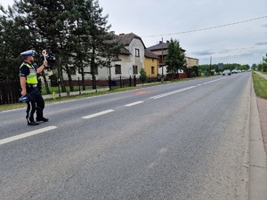 Zdjęcie przedstawia: policjanta ruchu drogowego podczas zatrzymywania pojazdu na drodze.