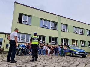 Zdjęcie przedstawia: mężczyznę, policjanta przed grupą dzieci.