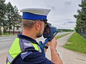 Zdjęcie przedstawia: policjant podczas pomiaru prędkości.