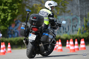 Zdjęcie przedstawia: policjanta, który jedzie na motocyklu.