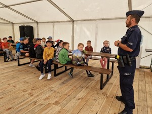 Zdjęcie przedstawia: policjanta mówiącego do grupy dzieci.