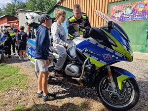 Zdjęcie przedstawia: chłopców stojących obok motocykla, widoczny jest także mundurowy.