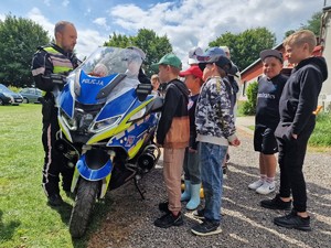 Zdjęcie przedstawia: grupę dzieci przed policjantem i motocyklem.