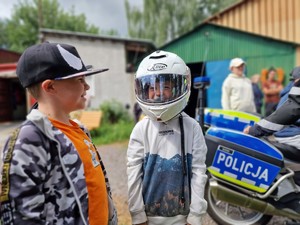 Zdjęcie przedstawia: chłopca który ma na głowie policyjny kask z motocykla.