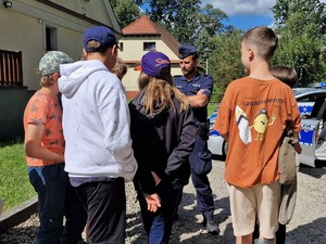 Zdjęcie przedstawia: grupę dzieci, które rozmawiają z policjantem.