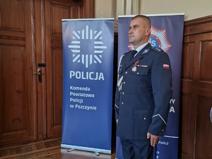 Zdjęcie przedstawia: umundurowanego policjnta, który stoi na baczność.