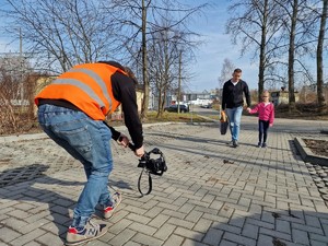 Zdjęcie przedstawia kamerzystę podczas nagrywania mężczyzny i dziewczynki podczas przejścia.