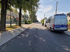 Zdjęcie przedstawia policyjny radiowóz podczas kontroli pojazdu typu bus.