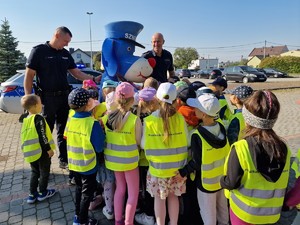 Zdjęcie przedstawia: grupę dzieci, która tuli się do policyjnej maskotki. Obok stoją policjanci.