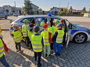 Zdjęcie przedstawia: grupę dzieci, które ustawiają się przy radiowozie, żeby go zobaczyć z bliska.