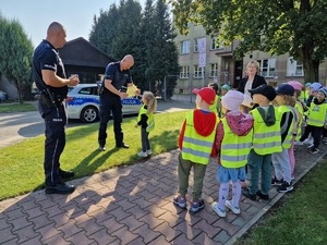 Zdjęcie przedstawia: dziecko które wręcza policjantowi laurkę.