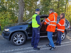 Zdjęcie przedstawia: 
Kierowcę wystawiającego rękę w kierunku przedstawicieli Kolei Śląskich oraz policjanta.