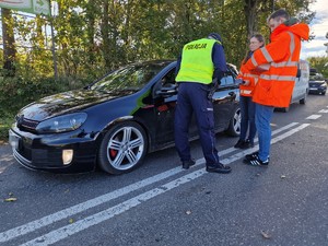 Zdjęcie przedstawia: 
Przedstawicieli Kolei Śląskich i policjanta pochylającego się do kierowcy samochodu, za nimi stoją dwa inne auta.