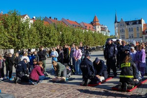 Na zdjęciu umundurowani policjanci, strażacy i uczestnicy ćwiczeń prowadzący resuscytację na fantomie