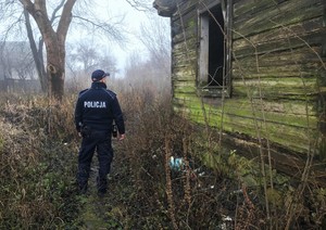 policjant stojący obok opuszczonego budynku