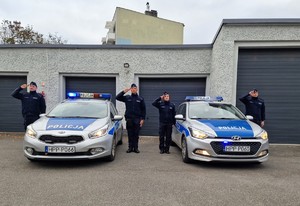 Zdjęcie przedstawia: salutujących policjantów przy radiowozach.