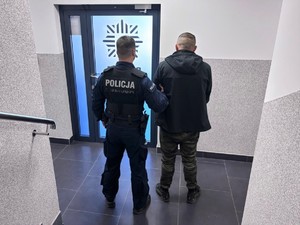 Zdjęcie przedstawia policjanta z zatrzymanym mężczyzną.