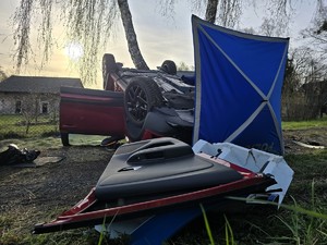 Zdjęcie przedstawia: dachujący czerwony pojazd osobowy