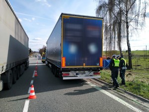 Zdjęcie przedstawia: dwóch funkcjonariuszy policji mierzących drogę hamowania pojazdu ciężarowego