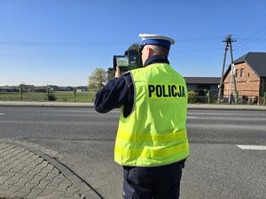 Zdjęcie przedstawia: funkcjonariusza policji mierzącego prędkość