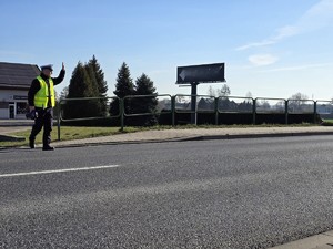 Zdjęcie przedstawia: funkcjonariusza policji zatrzymującego pojazd
