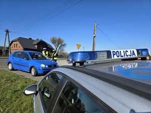 Zdjęcie przedstawia: dwóch funkcjonariuszy policji rozmawiających z kierowcą pojazdu osobowego