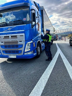 Zdjęcie przedstawia: funkcjonariusza policji sprawdzającego dokumenty