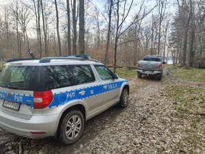 Zdjęcie przedstawia: radiowóz policyjny wraz z samochodem nadleśnictwa.