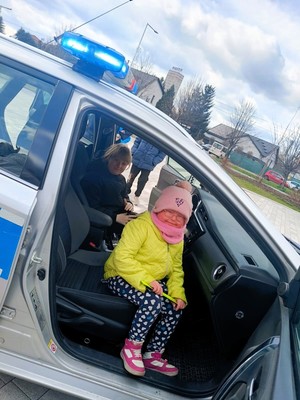 Zdjęcie przedstawia: dwie dziewczynki uśmiechające się w radiowozie.