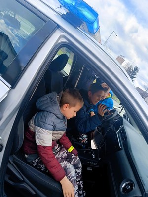 Zdjęcie przedstawia: dwóch chłopców w radiowozie.