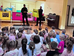 Zdjęcie przedstawia: dwóch umundurowanych policjantów rozmawiającymi z dziećmi.