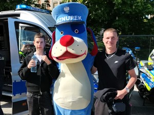 Zdjęcie przedstawia: dwóch nastolatków stojących z maskotką.