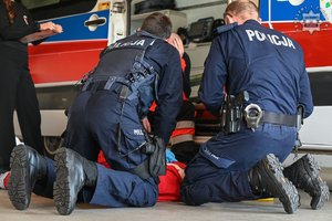 Umundurowani policjanci przy fantomie i karetce podczas zawodów