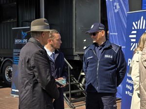 Zdjęcie przedstawia: policjanta rozmawiającego z dwoma mężczynami.