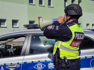 Zdjęcie przedstawia: policjanta mówiącego przez megafon