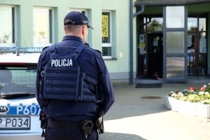 Zdjęcie przedstawia: policjanta z radiowozem