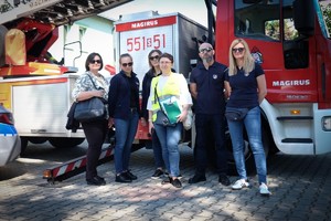 Zdjęcie przedstawia: ludzi przy wozach strażackich