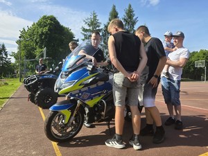 Zdjęcie przedstawia: ludzi oglądających motocykl policyjny