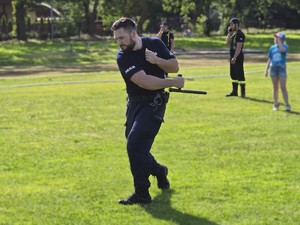 Zdjęcie przedstawia: policjanta wykonującego zamach pałką