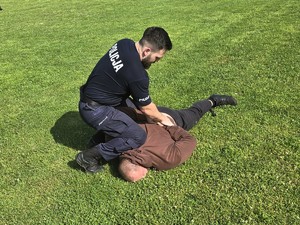 Zdjęcie przedstawia: policjanta oraz mężczyznę który leży obezwładniony