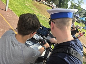 Zdjęcie przedstawia: policjanta pokazującego dziecku quada policyjnego