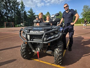 Zdjęcie przedstawia: dziecko siedzące na quadzie oraz policjanta