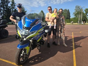 Zdjęcie przedstawia: rodzinę z policyjnym motocyklem